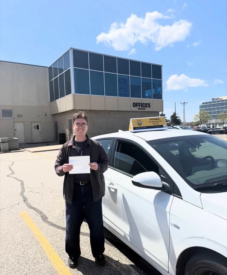 A Rydbie student holding their pass slip beside a Rydbie car