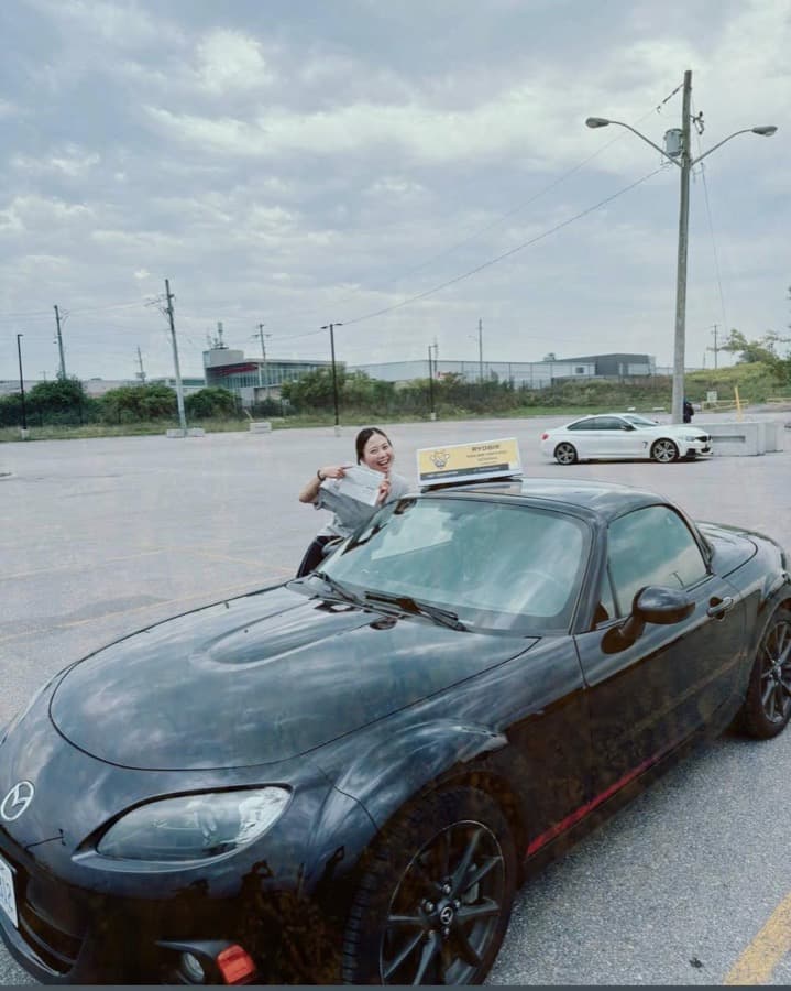 A Rydbie student leaning out of a Rydbie car holding their pass slip