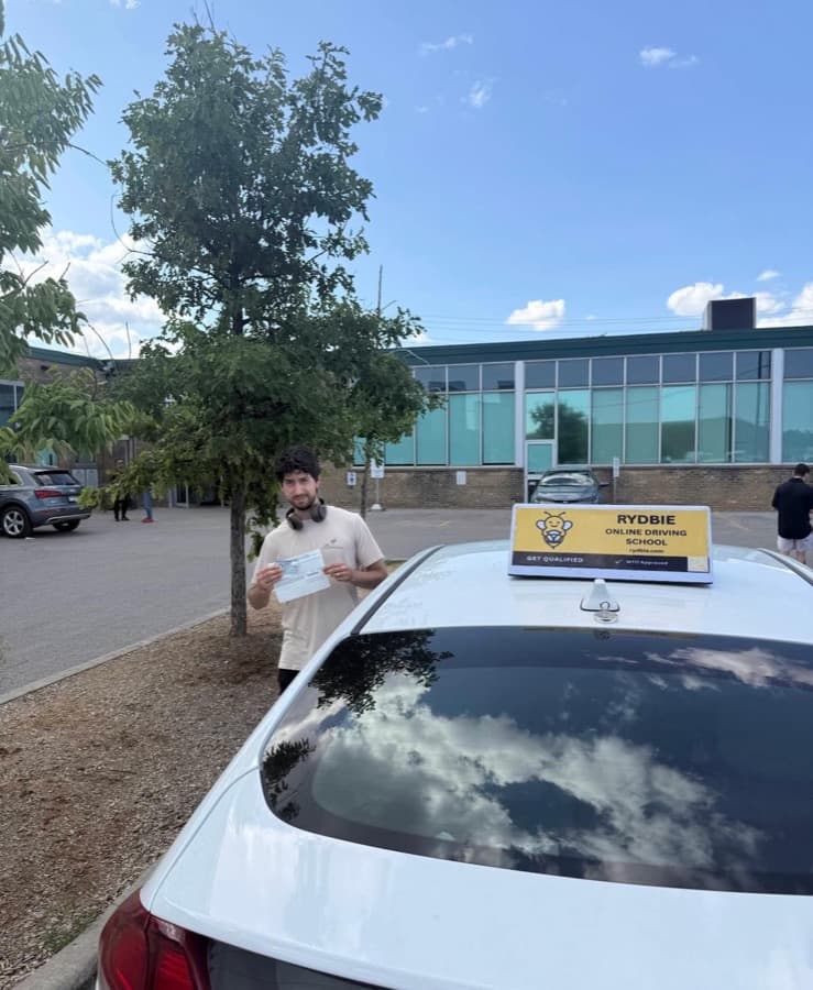 A Rydbie student holding their pass slip beside a Rydbie car
