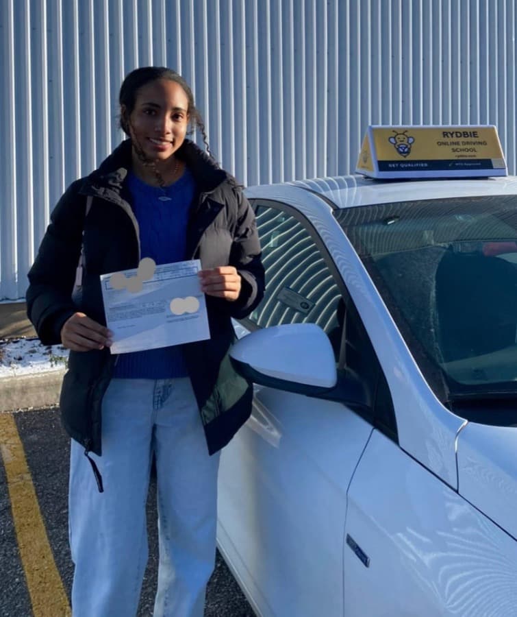 A Rydbie student holding their pass slip beside a Rydbie car