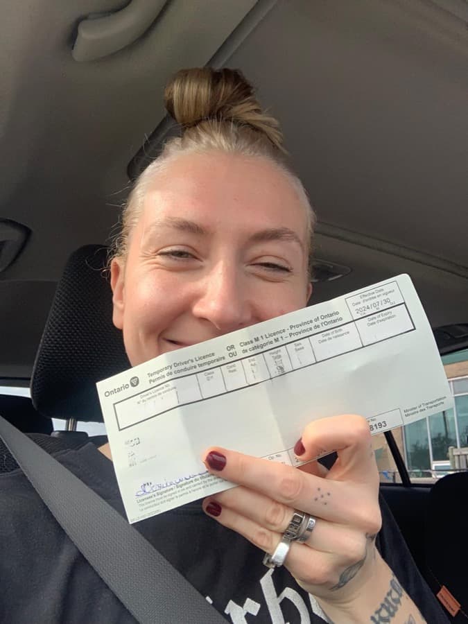 A Rydbie student in the car holding their new temporary Ontario licence